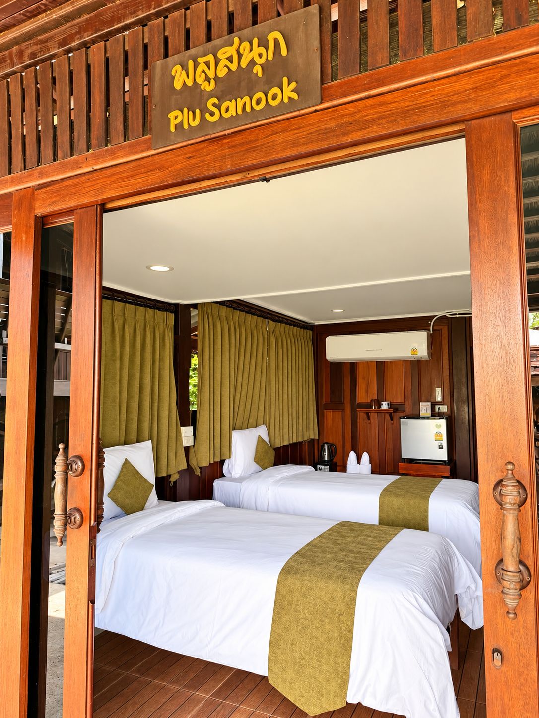 A hotel room with two beds, a wooden door frame, and a sign above the door.
