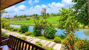 A wooden deck with a view of a river, greenery, and a clear sky.