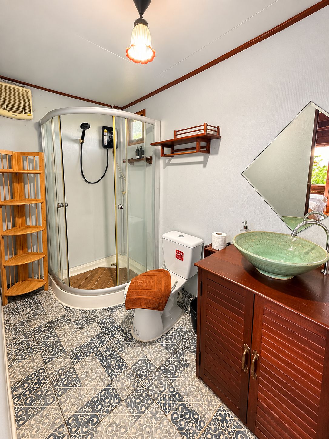 A bathroom with a shower, toilet, sink, and a mirror.
