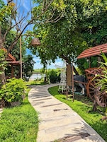 Un sentier de jardin agrémenté d’une structure en bois rustique, d’une enseigne en métal et d’un chariot décoratif.