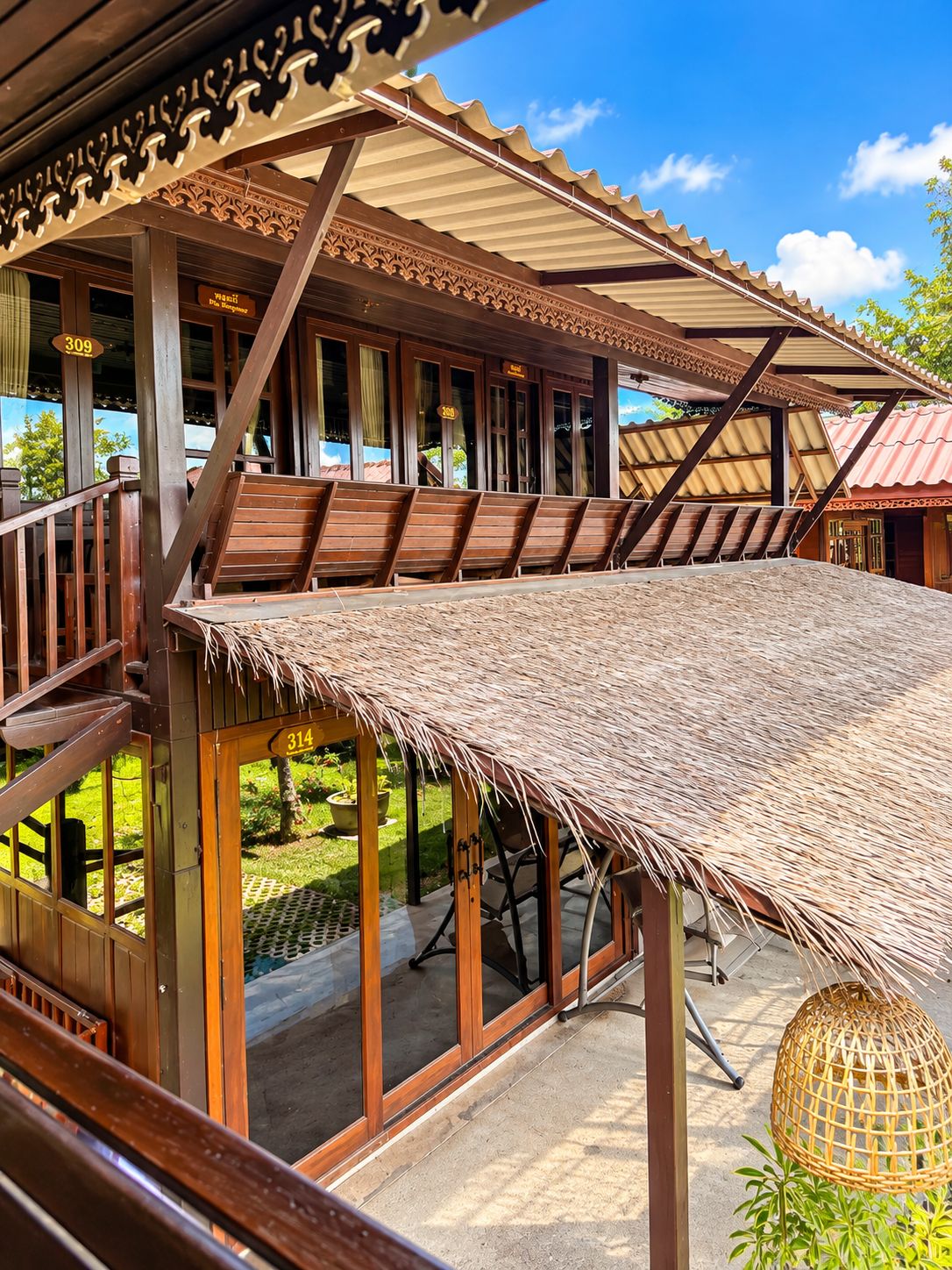 A covered outdoor seating area with wooden benches and a thatched roof.