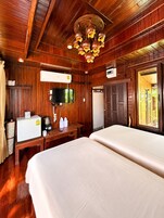 Una habitación con piso de madera, una cama, un televisor, una cafetera y una ventana.