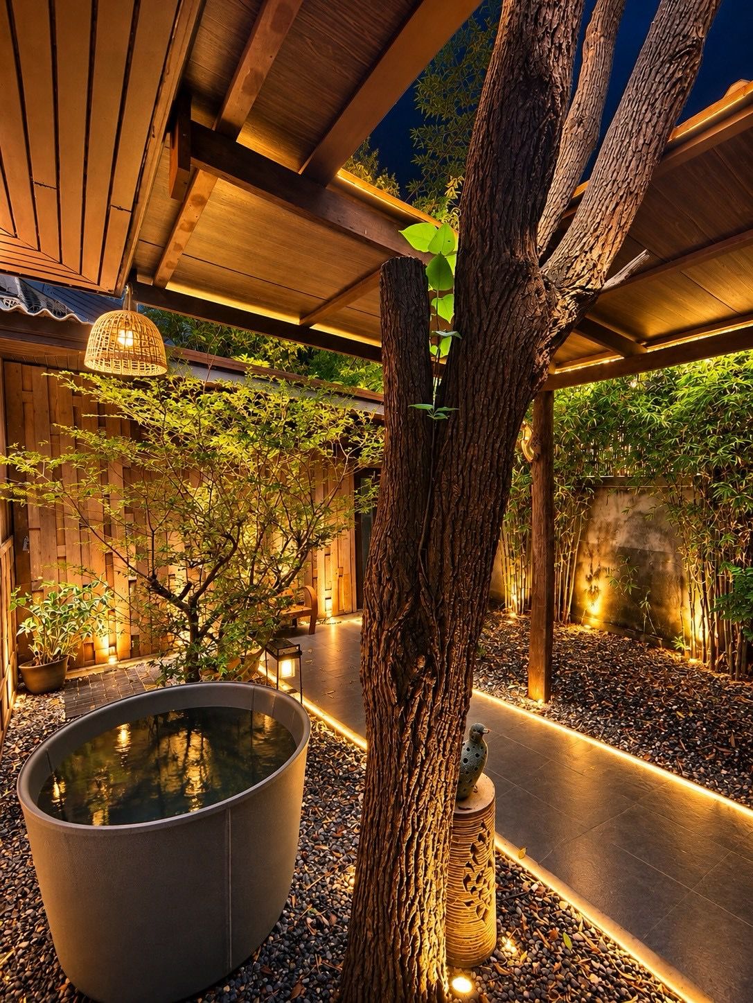 Ein ruhiger Außenbereich mit einer Holz-Pergola, einem großen Pflanzgefäß mit einem Baum und einem Wasserspiel.