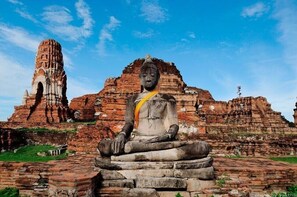 A large Buddha statue in front of ancient brick ruins. - Pludhaya Resort & Spa (Ayutthaya)