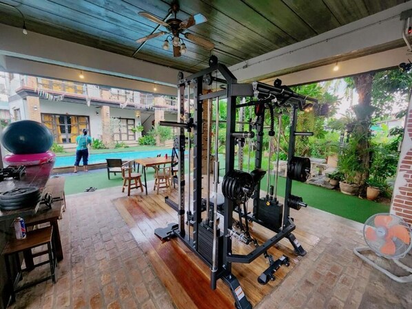An outdoor gym with exercise equipment, a pool, and a patio area.