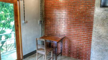 A corner room with a brick wall, a wooden table, and a chair.