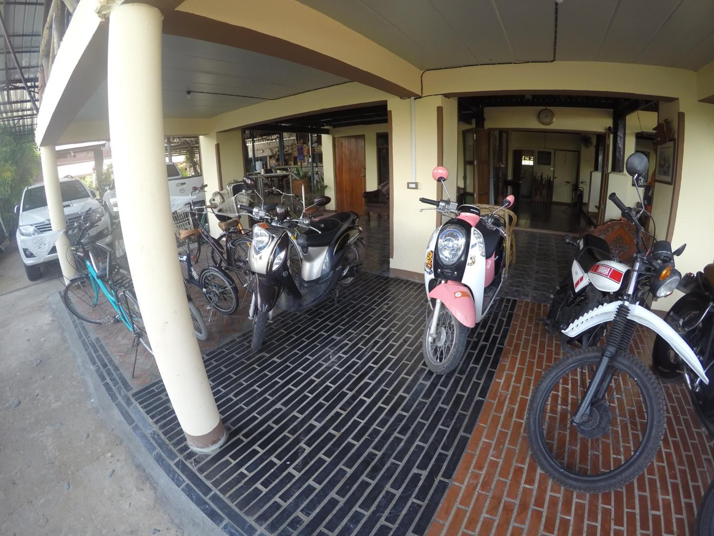 Un espace de stationnement couvert où sont garées plusieurs motos et plusieurs vélos.