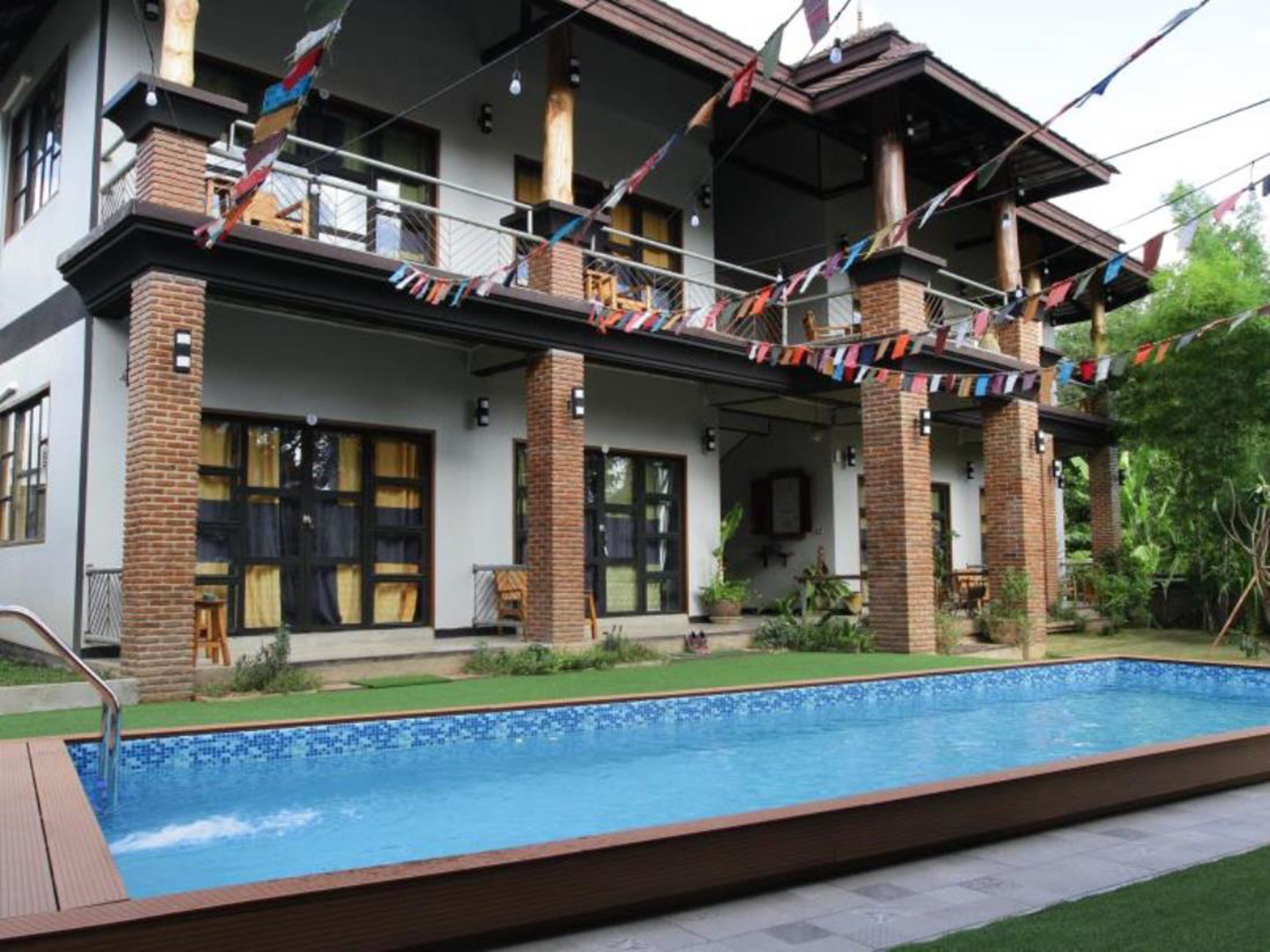 A two-story house with a swimming pool in the foreground.