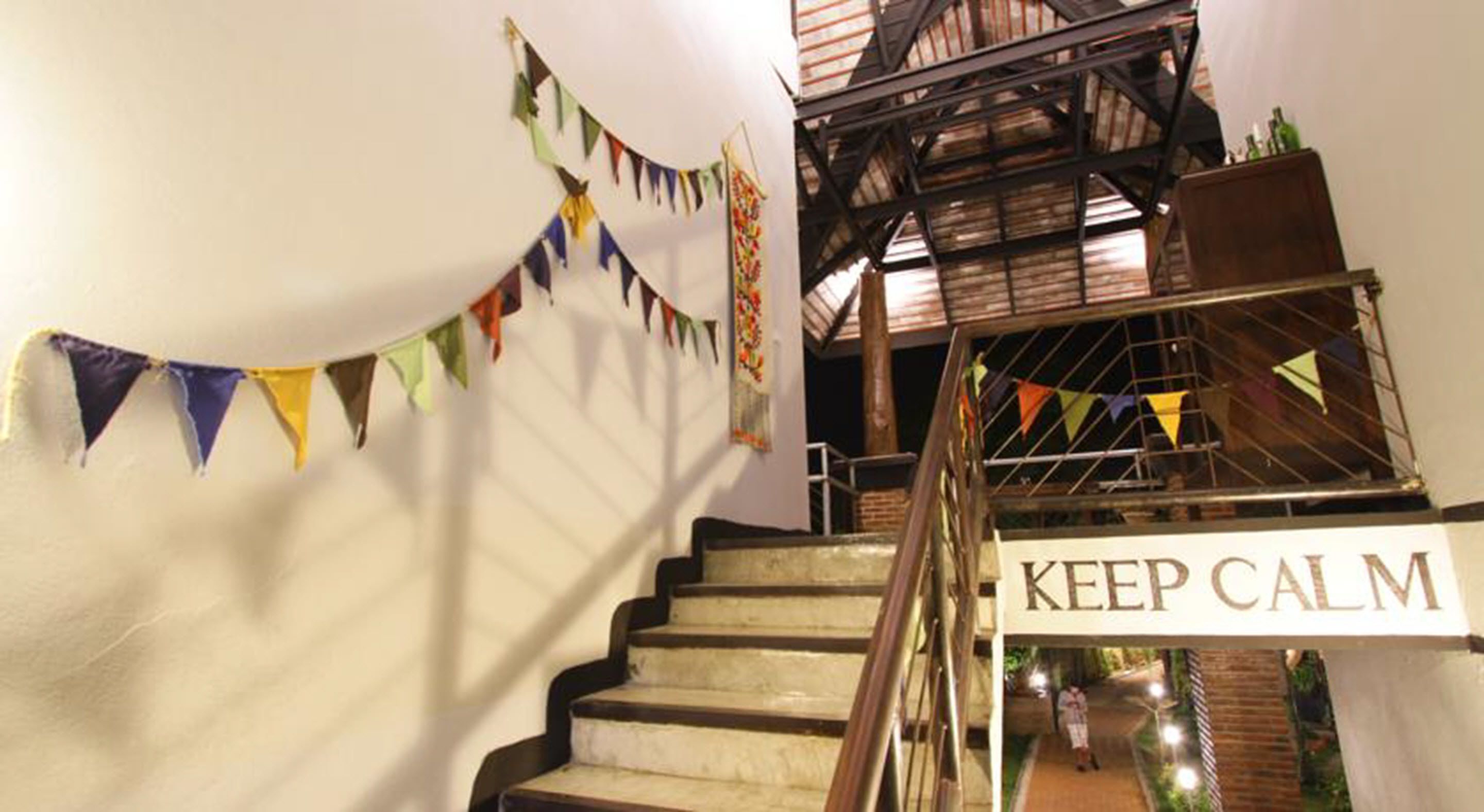 Una scala con un cartello riportante la scritta "KEEP CALM", ringhiere in legno e festoni colorati.
