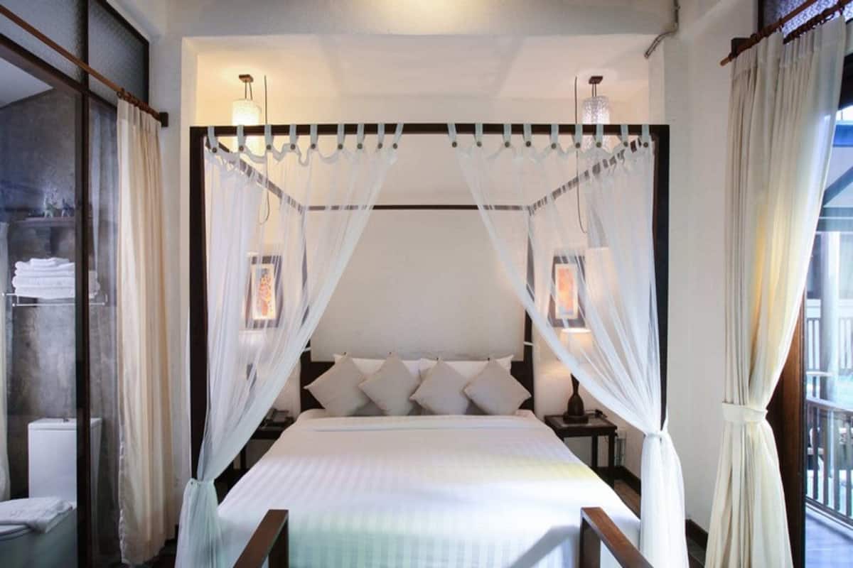 Een slaapkamer met een hemelbed, bedlampjes en uitzicht.