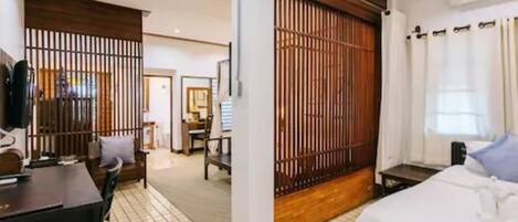 A hotel room with a bed, a desk, a chair, a TV, and a sliding door.