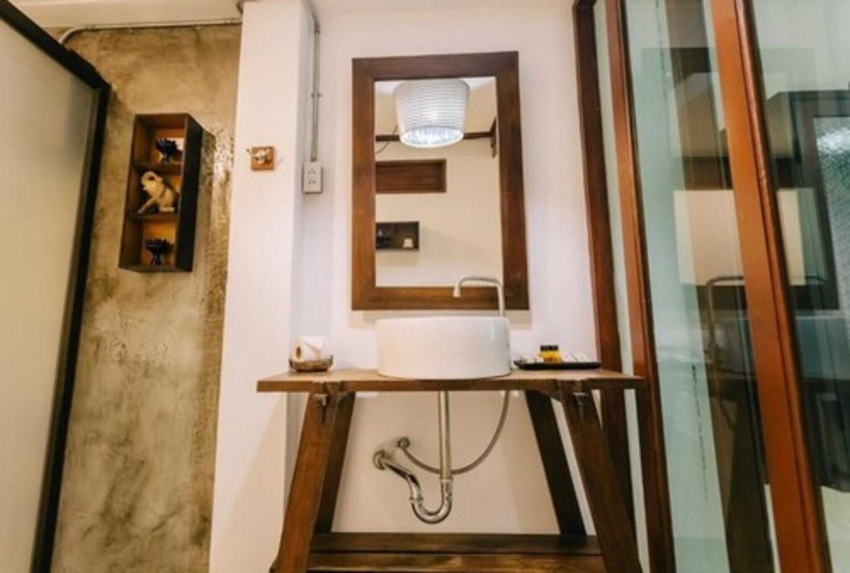 A compact bathroom with a wooden vanity, a mirror, and a built-in sink.