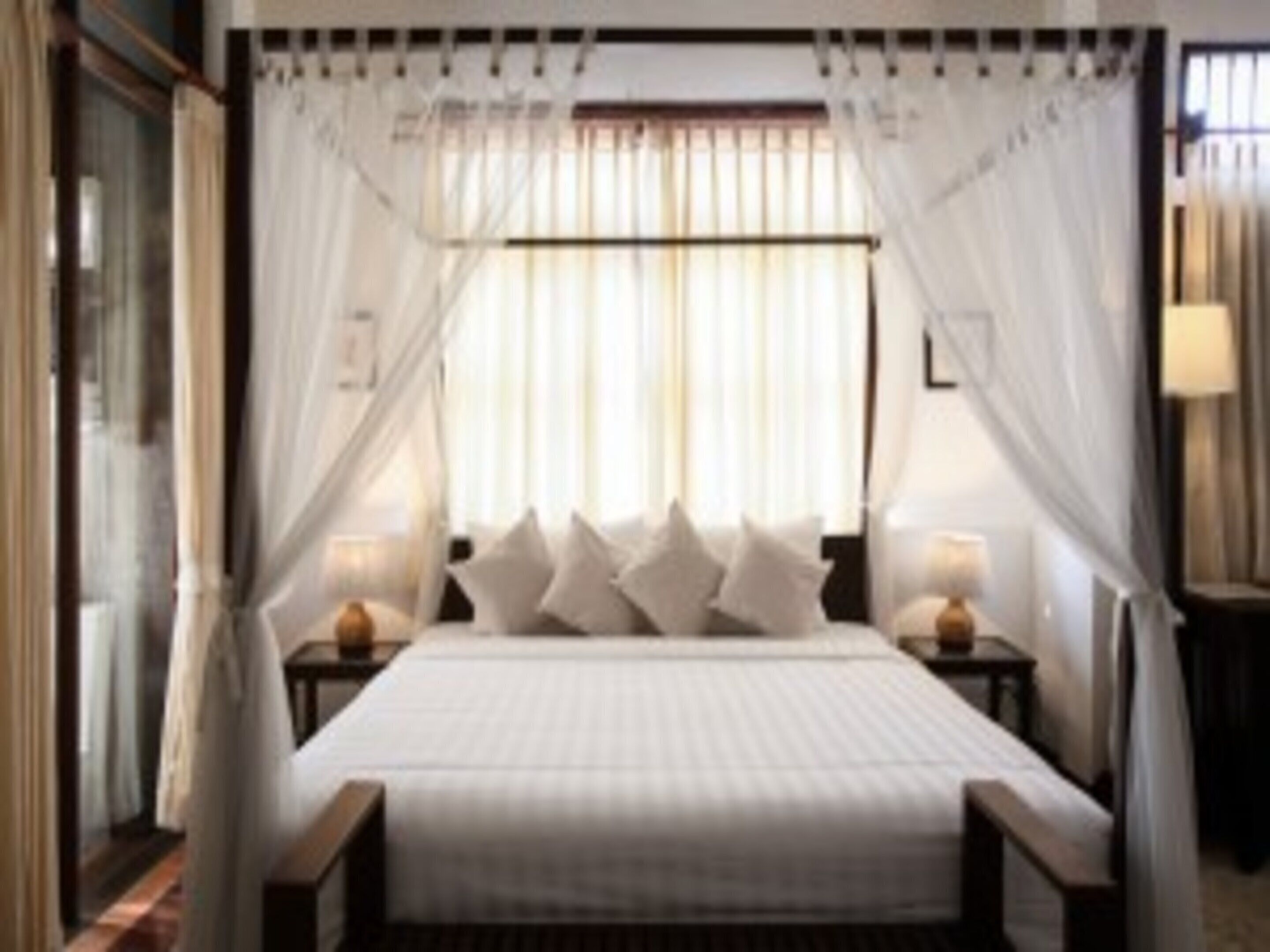 A bedroom with a bed, curtains, and bedside lamps.