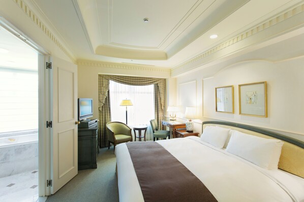 A hotel room with a large bed, a desk with a computer, a chair, a television, and a window with curtains. - Hotel the Manhattan (Chiba)
