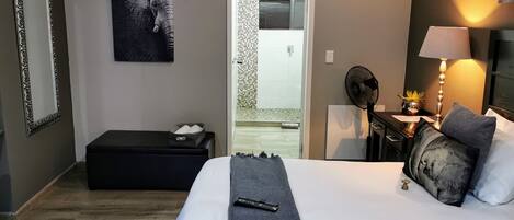 A hotel room with a bed, bedside table, lamp, and a picture of an elephant on the wall.
