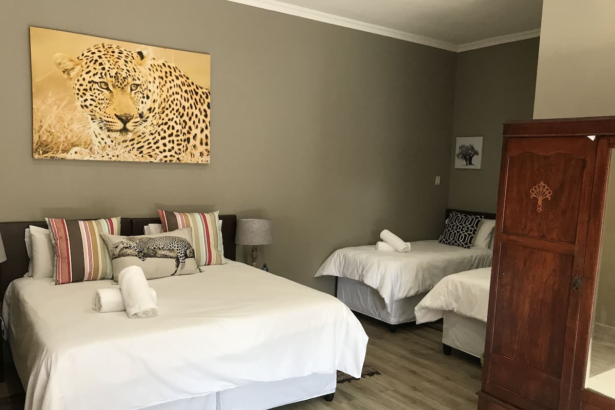 Habitación de hotel con dos camas, un armario de madera y una obra de arte con temática de leopardo en la pared.