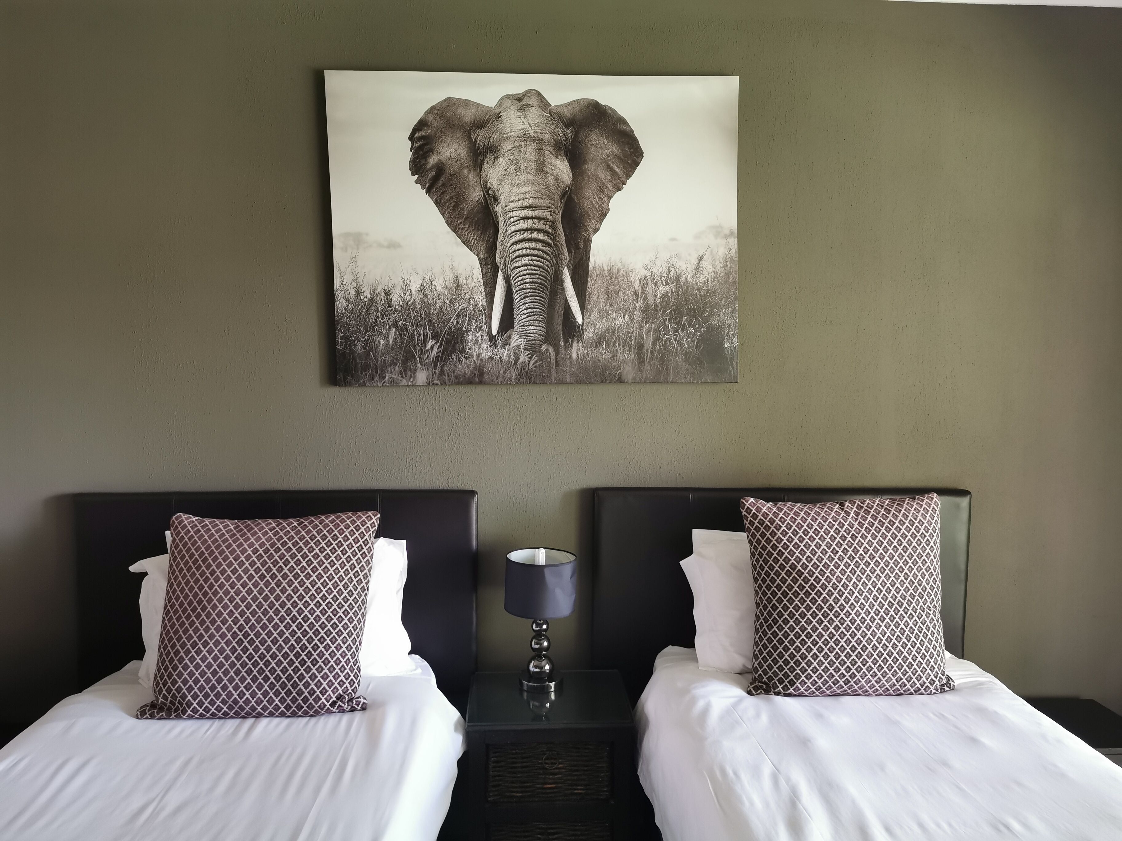 A hotel room with two beds, each with patterned pillows and a nightstand with a lamp.