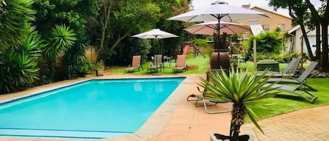 Una piscina al aire libre, sillones reclinables de piscina