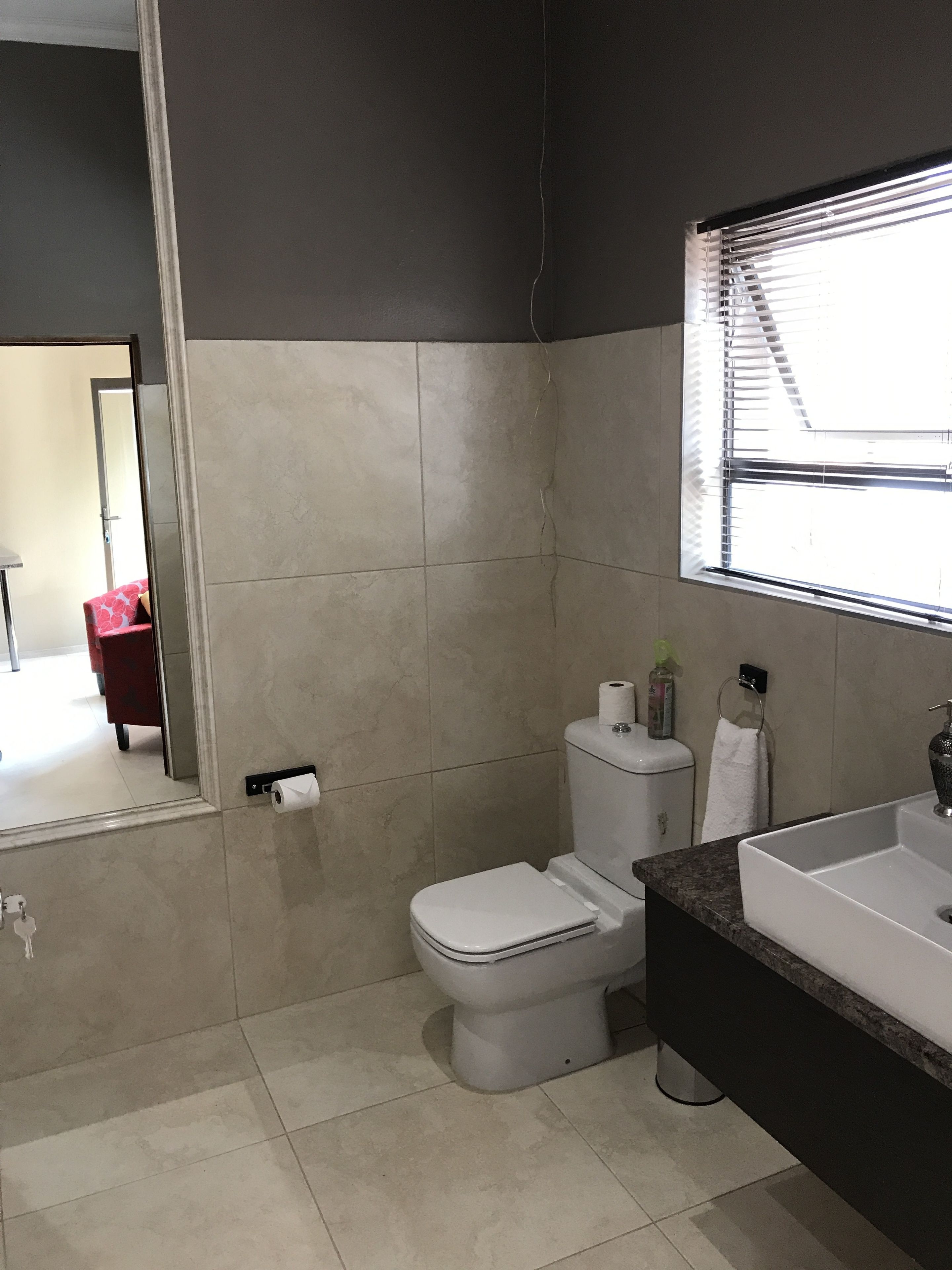 Un baño moderno con inodoro, lavamanos y espejo.
