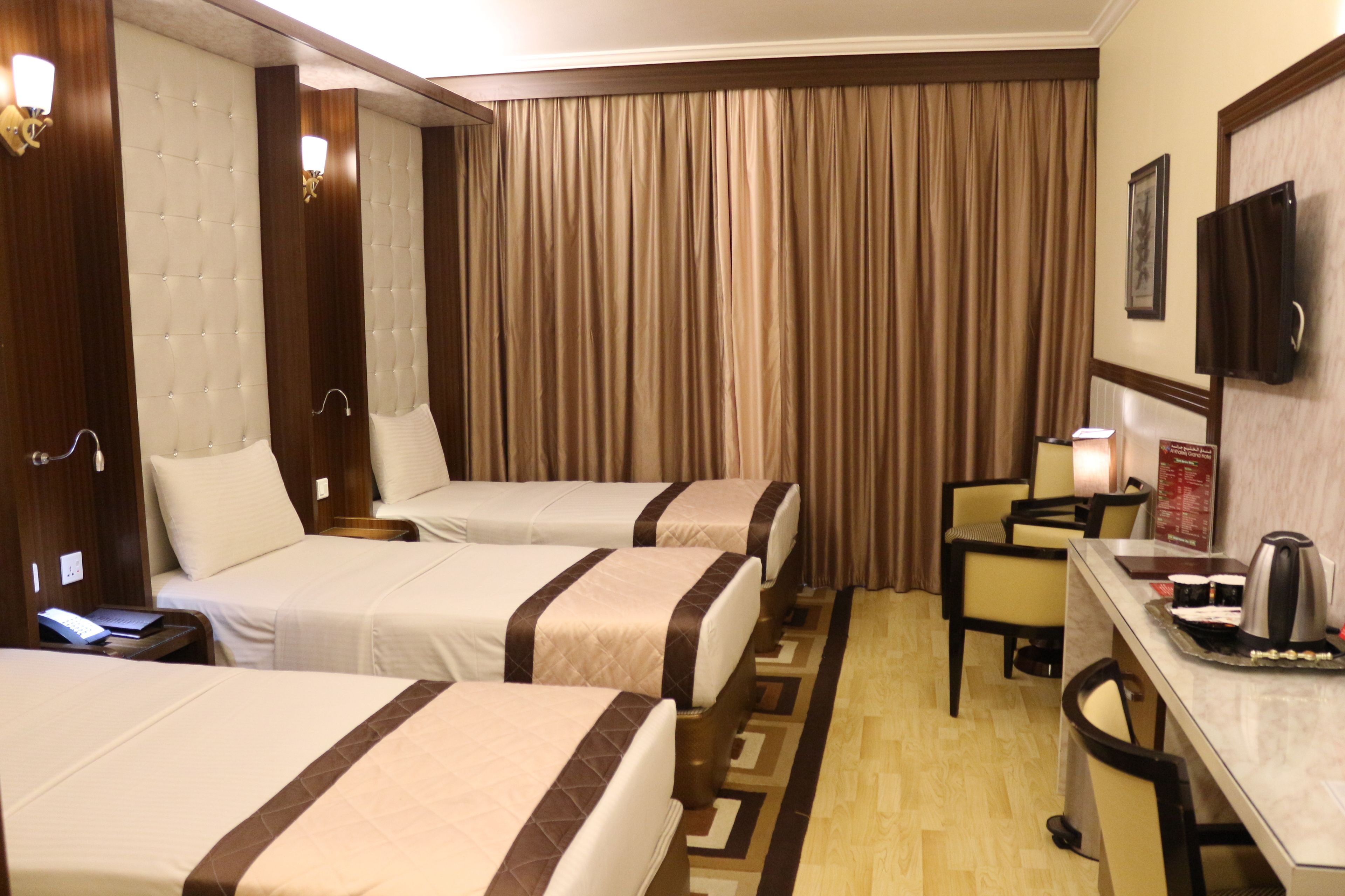 Ein Hotelzimmer mit zwei Betten, einem Schreibtisch, einem Sessel, einem Fernseher und einer Minibar.