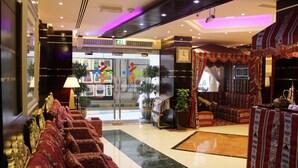 A hotel lobby with a reception desk, seating area, and a clock on the wall. - Al Khaleej Grand Hotel (Dubai)