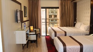 A hotel room with two beds, a desk with a chair, a TV, and a window with curtains. - Al Khaleej Grand Hotel (Dubai)