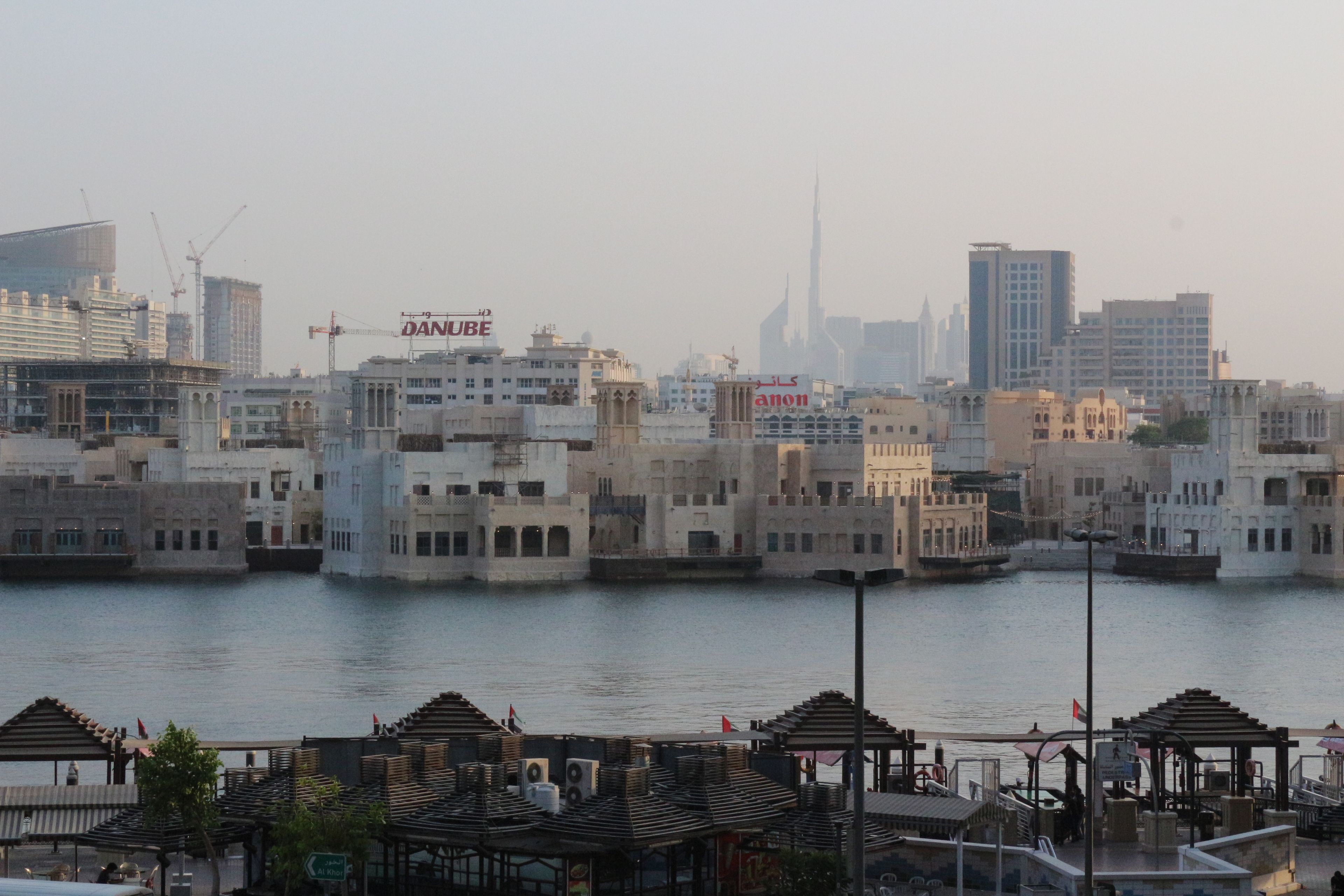 A waterfront cityscape with a mix of modern and traditional architecture, including a prominent tower and various commercial buildings.