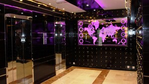 A modern lobby with a large digital world map display, a glass elevator, and a patterned floor. - Al Khaleej Grand Hotel (Dubai)