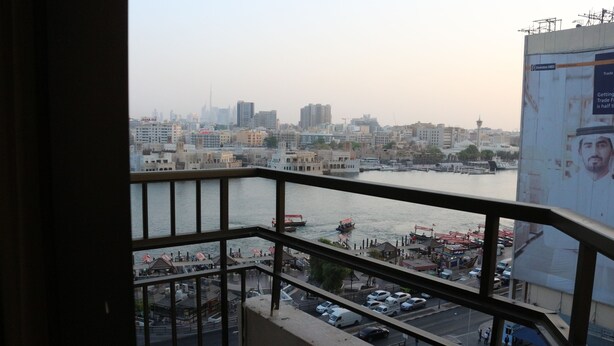 A cityscape with a river, buildings, and a view from a balcony. - Al Khaleej Grand Hotel (Dubai)