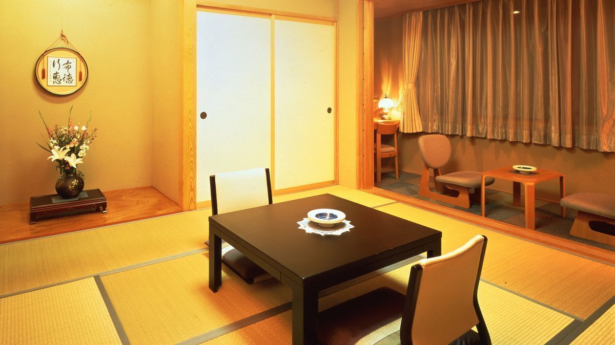 A traditional Japanese room with tatami flooring, a low table with a decorative plate, a chair, and a sliding door.