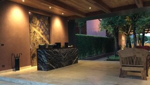 A reception area with a marble counter, steps leading up to it, and a wooden bench. - The Glory River Kwai Hotel (Kanchanaburi)