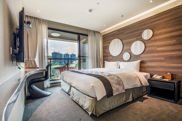 A modern hotel room with a large bed, a desk, a TV, and a view of the cityscape. - Green World Hotel Songshan (Taipei)