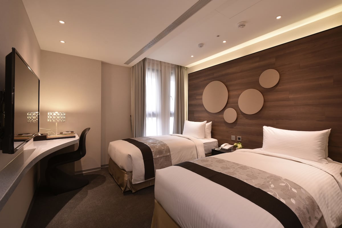 Ein modernes Hotelzimmer mit zwei Betten, einem Schreibtisch, einem großen Spiegel und einer Wand mit runden Dekorationen.