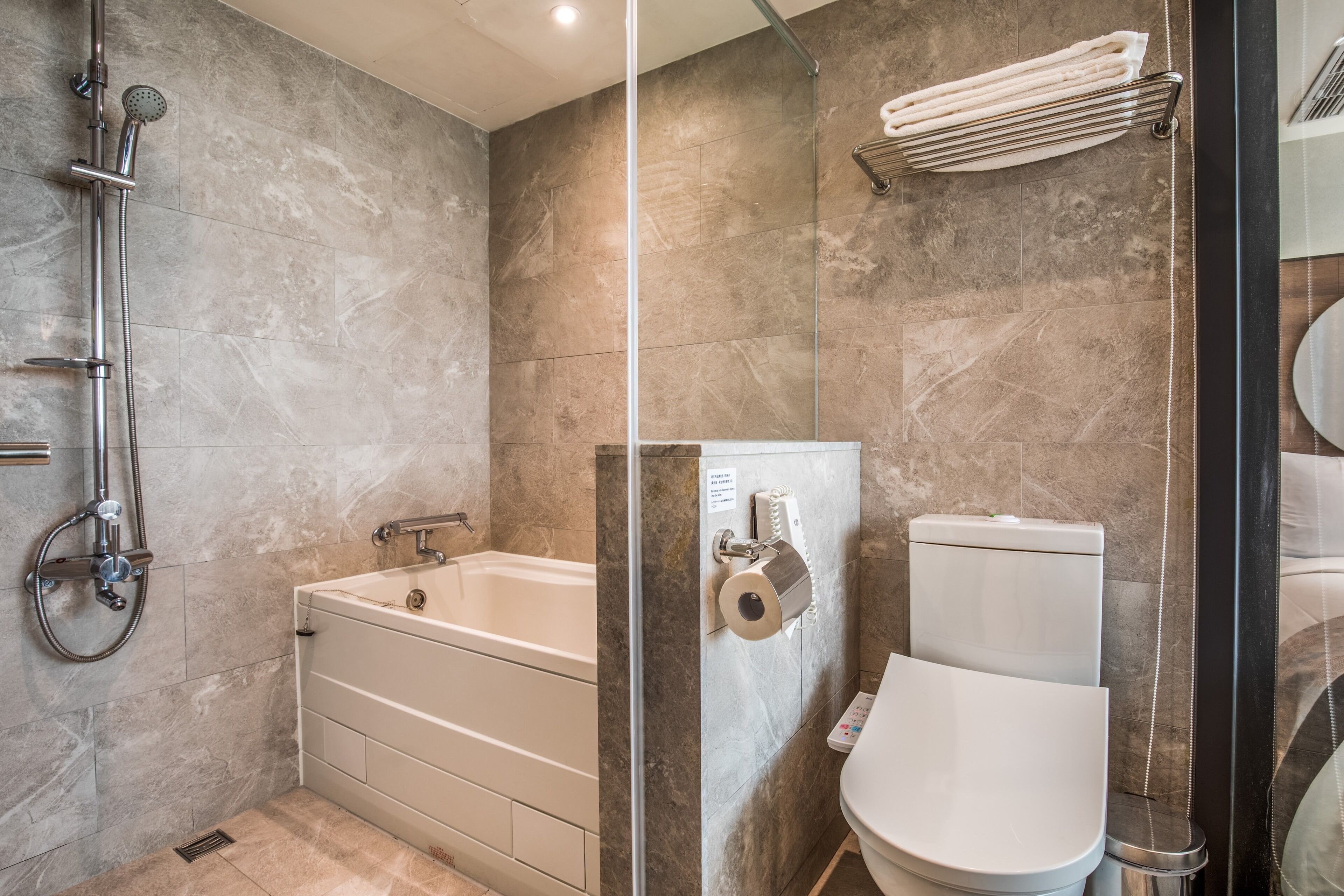 A modern bathroom with a bathtub, toilet, and shower.