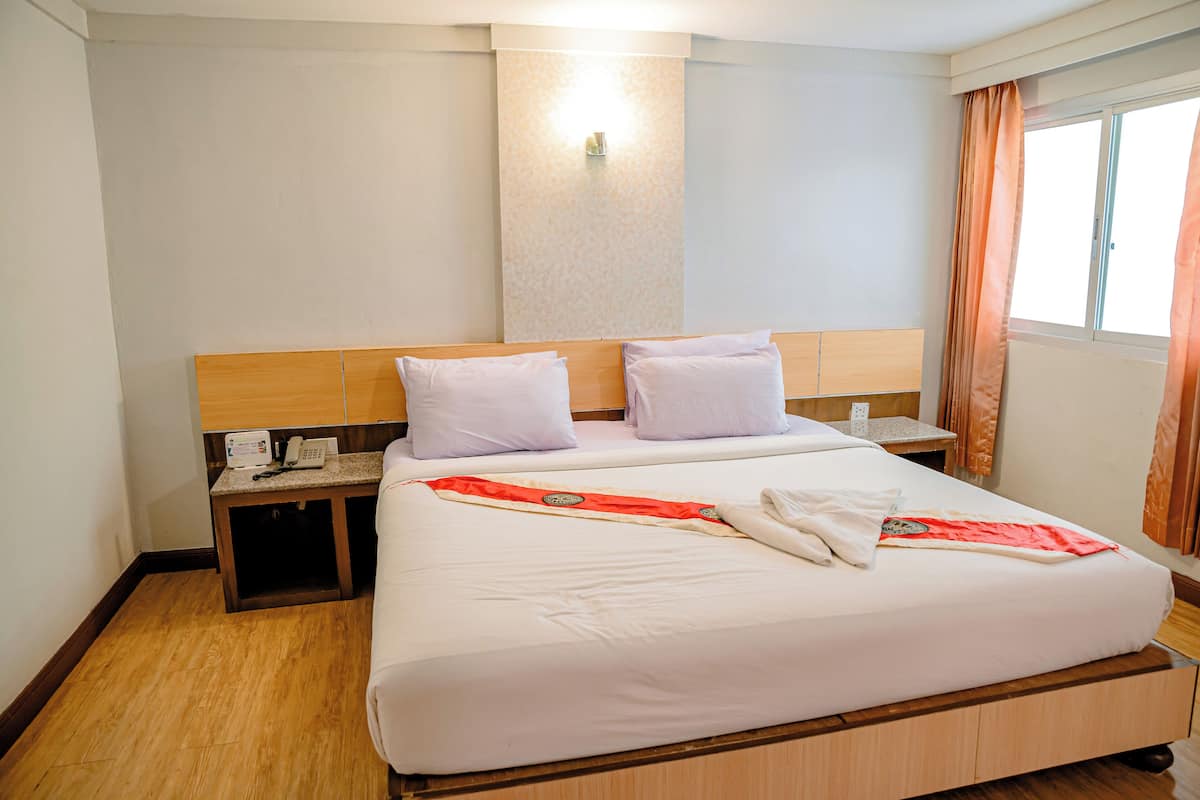 A hotel room with a large bed, a bedside table with a phone, and a window with curtains.