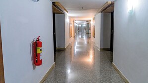 A long, narrow hotel corridor with a fire extinguisher mounted on the wall, doors on both sides, and a polished floor. - Satit Grand View Hotel (Sadao)