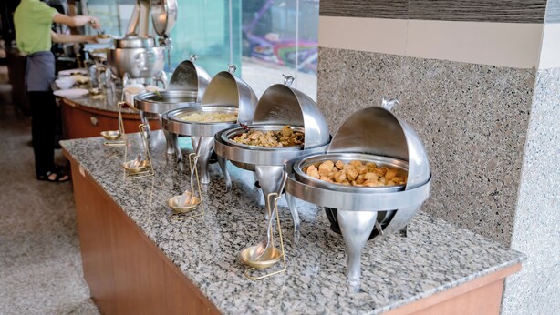 A buffet setup with multiple food dispensers on a granite countertop. - Satit Grand View Hotel (Sadao)