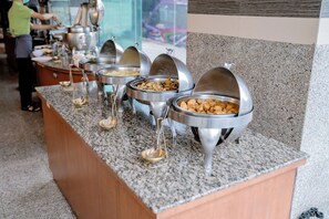 A buffet setup with multiple food dispensers on a granite countertop. - Satit Grand View Hotel (Sadao)