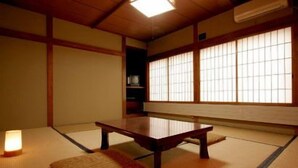Una habitación japonesa tradicional con suelo de tatami, una baja mesa de madera y puertas correderas shoji.