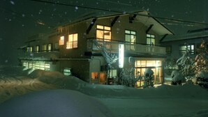 Una casa de dos pisos con un balcón, rodeada de nieve.
