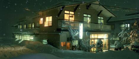 A two-story house with a balcony, surrounded by snow.
