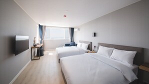 Een hotelkamer met twee bedden, een televisie, een bureau en een raam met gordijnen.
