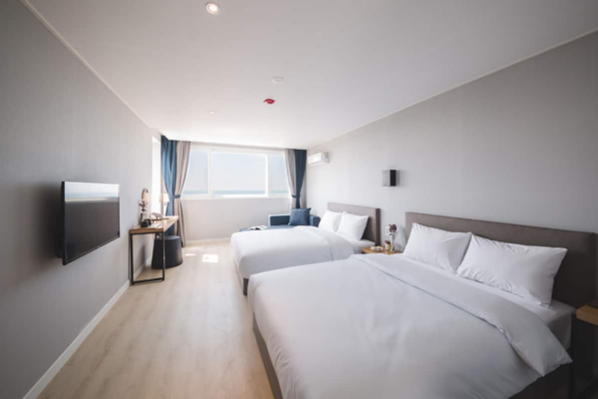 Een hotelkamer met twee bedden, een televisie, een bureau en een raam met gordijnen.