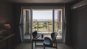 Een kamer met een groot raam, een bureau met een laptop en een stoel.