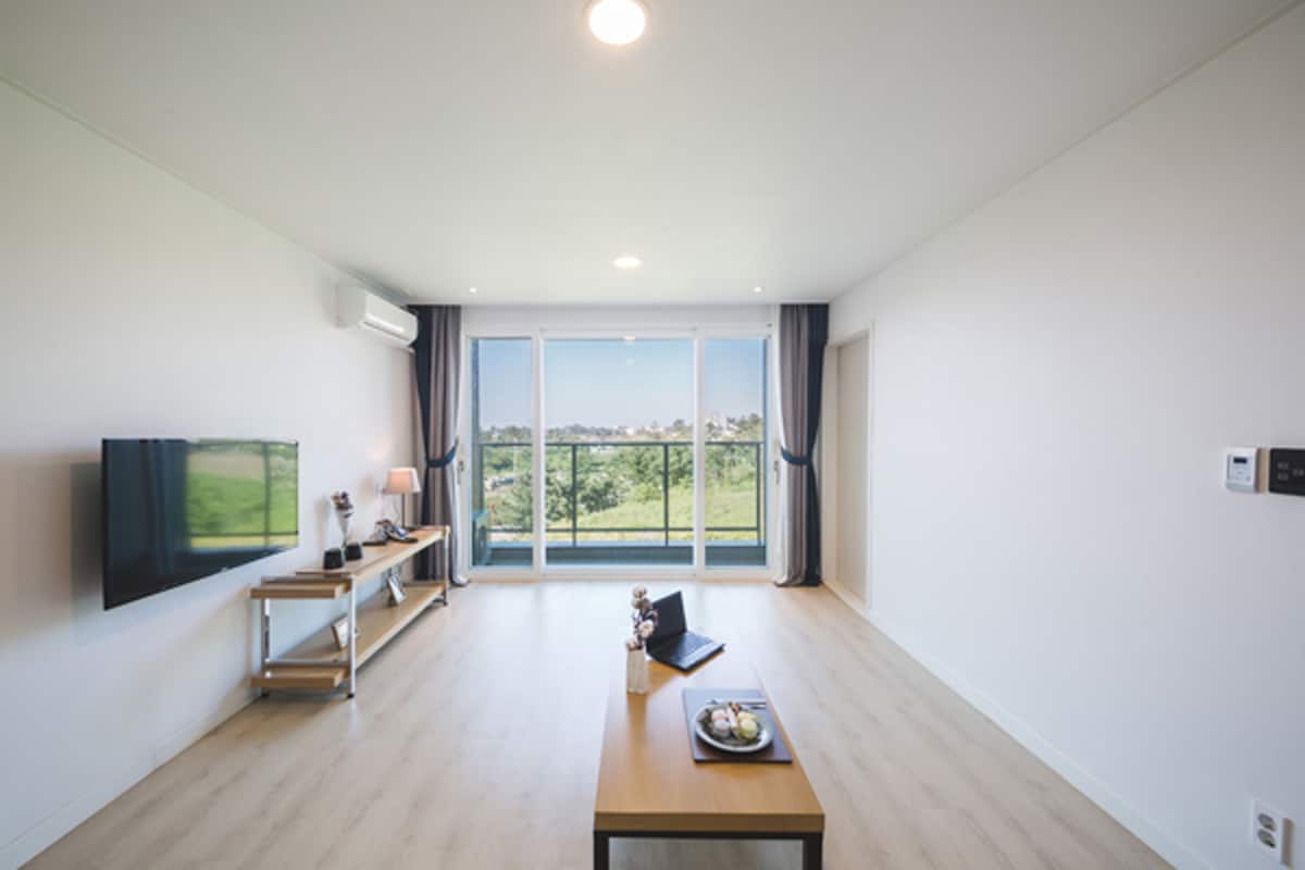 Een moderne woonkamer met een grote flatscreen televisie, een houten salontafel en een laptop.
