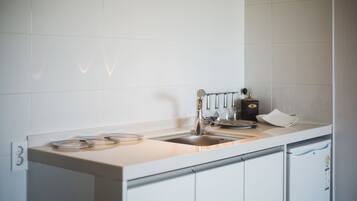 A modern kitchen with white cabinets, a stainless steel sink, and a coffee machine.