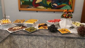 A buffet table with various food items and a decorative vase with flowers. - Rodos Blue Resort (Rhodes)
