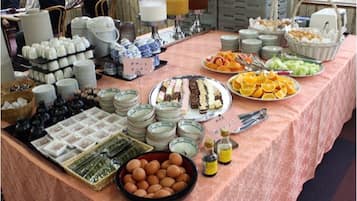 A buffet table with various food items, including fruits, pastries, and condiments.