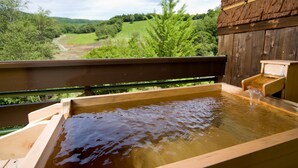 A wooden hot tub with a wooden bench and a small waterfall feature.