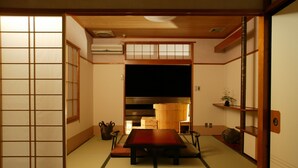A traditional Japanese room with tatami flooring, a low table, and sliding doors.